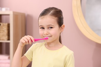 Photo of Cute girl brushing her teeth in bathroom