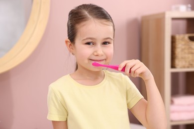 Photo of Cute girl brushing her teeth in bathroom