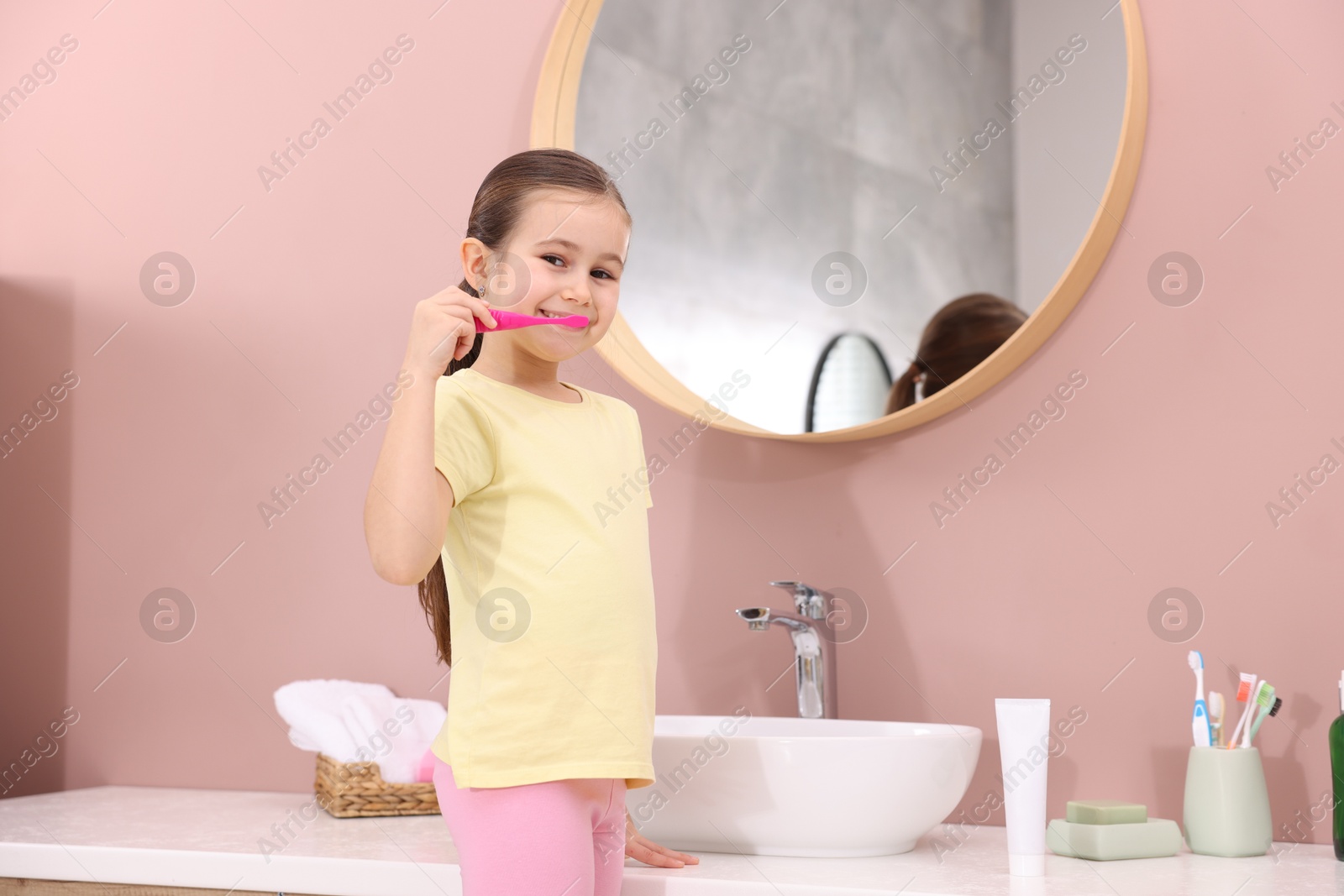 Photo of Cute girl brushing her teeth in bathroom