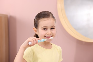 Photo of Cute girl brushing her teeth in bathroom