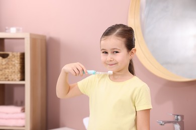 Photo of Cute girl with toothbrush in bathroom. Personal hygiene