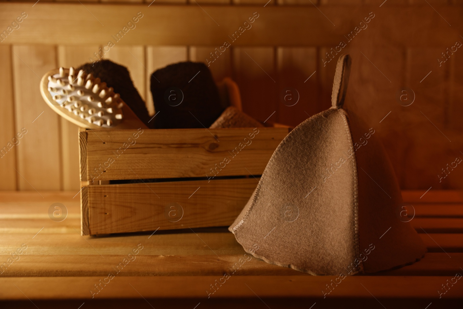 Photo of Crate with bath accessories and felt wool hat on wooden bench in sauna