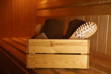 Photo of Crate with bath accessories on wooden bench in sauna