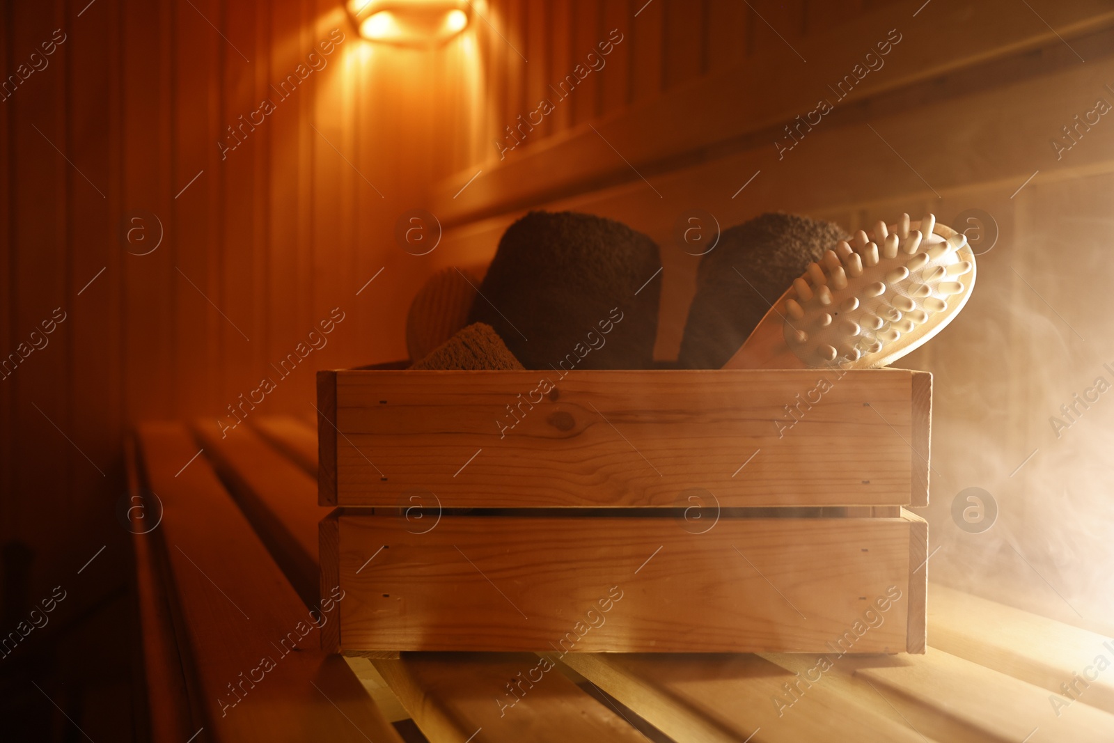 Photo of Crate with bath accessories on wooden bench in sauna