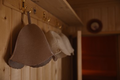 Photo of Felt wool hats on hangers in sauna. Space for text