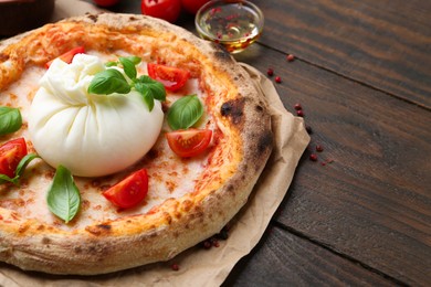 Photo of Delicious pizza with burrata cheese, basil and tomatoes on wooden table, closeup. Space for text