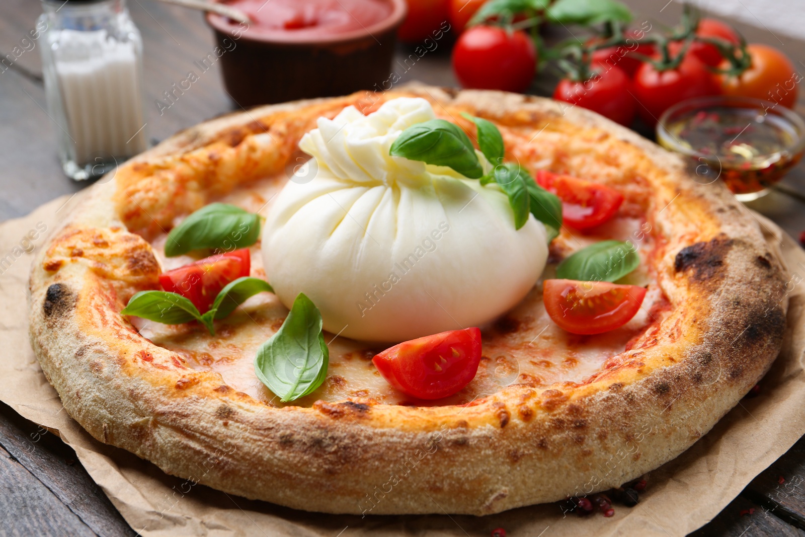 Photo of Delicious pizza with burrata cheese, basil and tomatoes on table, closeup