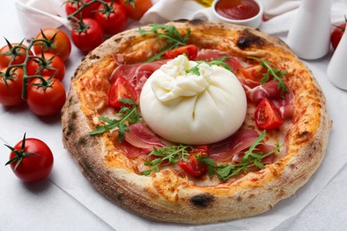 Photo of Delicious pizza with burrata cheese, arugula, tomatoes and ham on light grey table, closeup