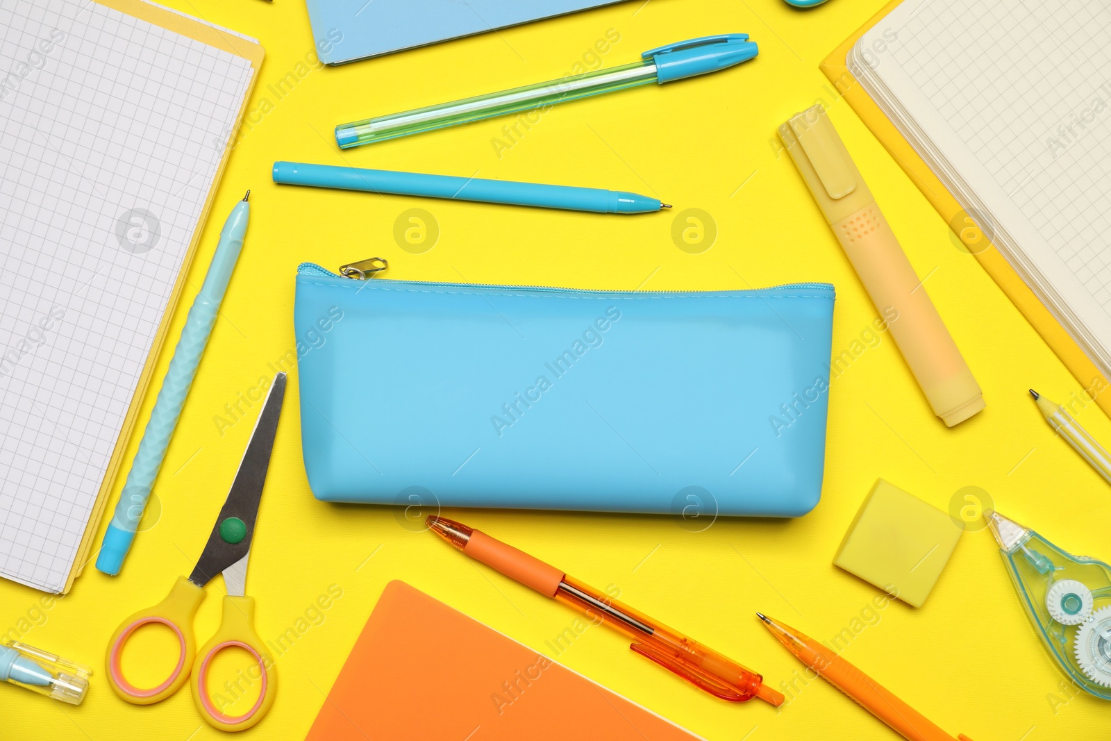 Pencil case and different stationery on yellow background, flat lay Photo of Pencil case and different stationery on yellow background, flat lay