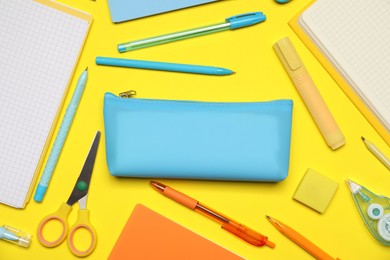 Photo of Pencil case and different stationery on yellow background, flat lay