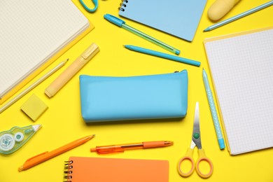 Photo of Pencil case and different stationery on yellow background, flat lay