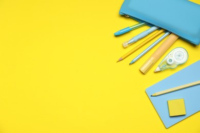 Photo of Pencil case and different stationery on yellow background, flat lay. Space for text