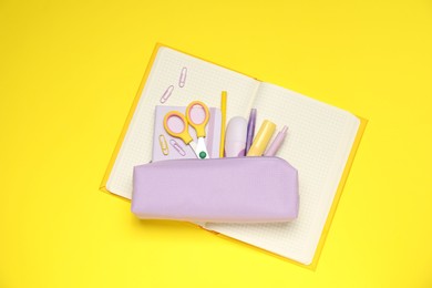 Photo of Pencil case and different stationery on yellow background, top view