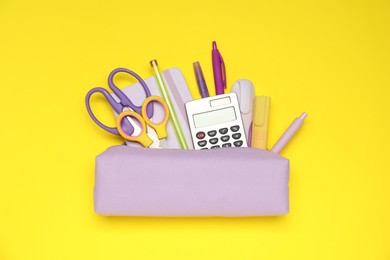 Photo of Pencil case and different stationery on yellow background, flat lay