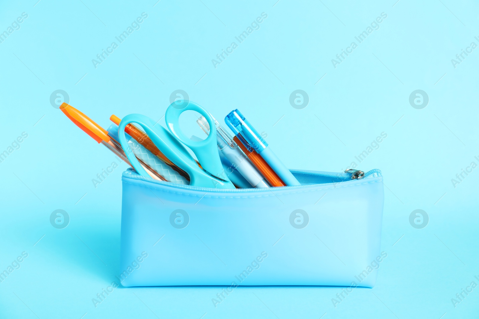 Different stationery in pencil case on light blue background Photo of Different stationery in pencil case on light blue background