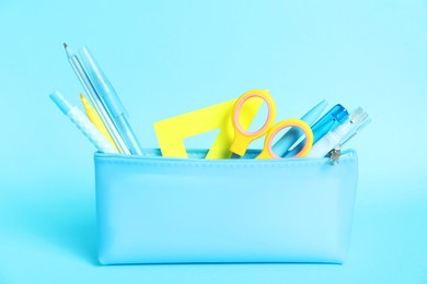 Photo of Different stationery in pencil case on light blue background