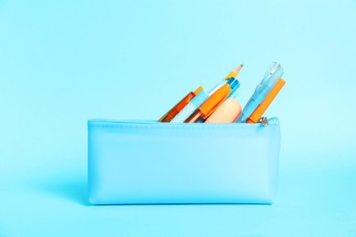 Photo of Different stationery in pencil case on light blue background