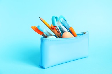 Photo of Different stationery in pencil case on light blue background, closeup