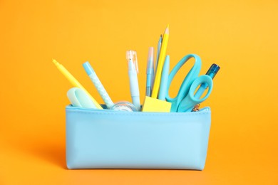 Photo of Different stationery in pencil case on orange background