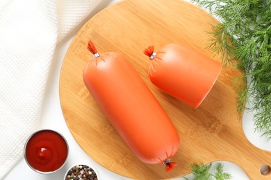 Photo of Tasty boiled sausages, ketchup and spices on white table, top view