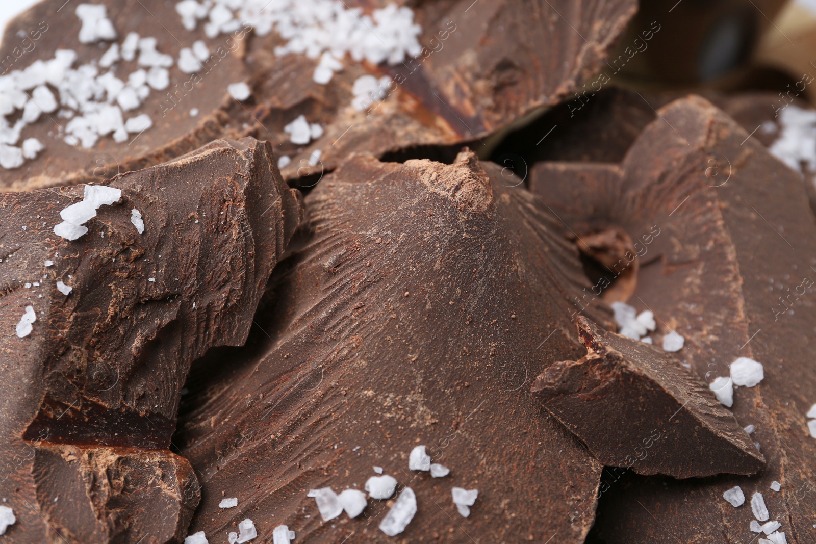 Photo of Pieces of tasty chocolate with salt on table, closeup