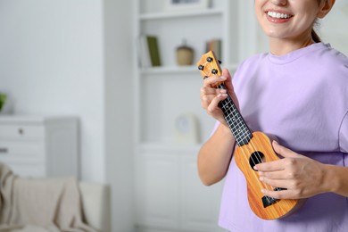 Photo of Woman playing ukulele at home, closeup. Space for text