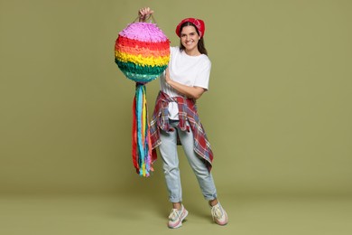 Happy woman with colorful pinata on green background