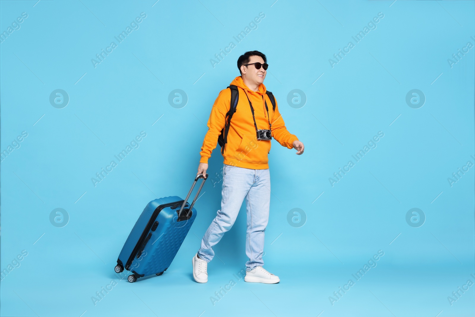 Photo of Traveller with suitcase on light blue background