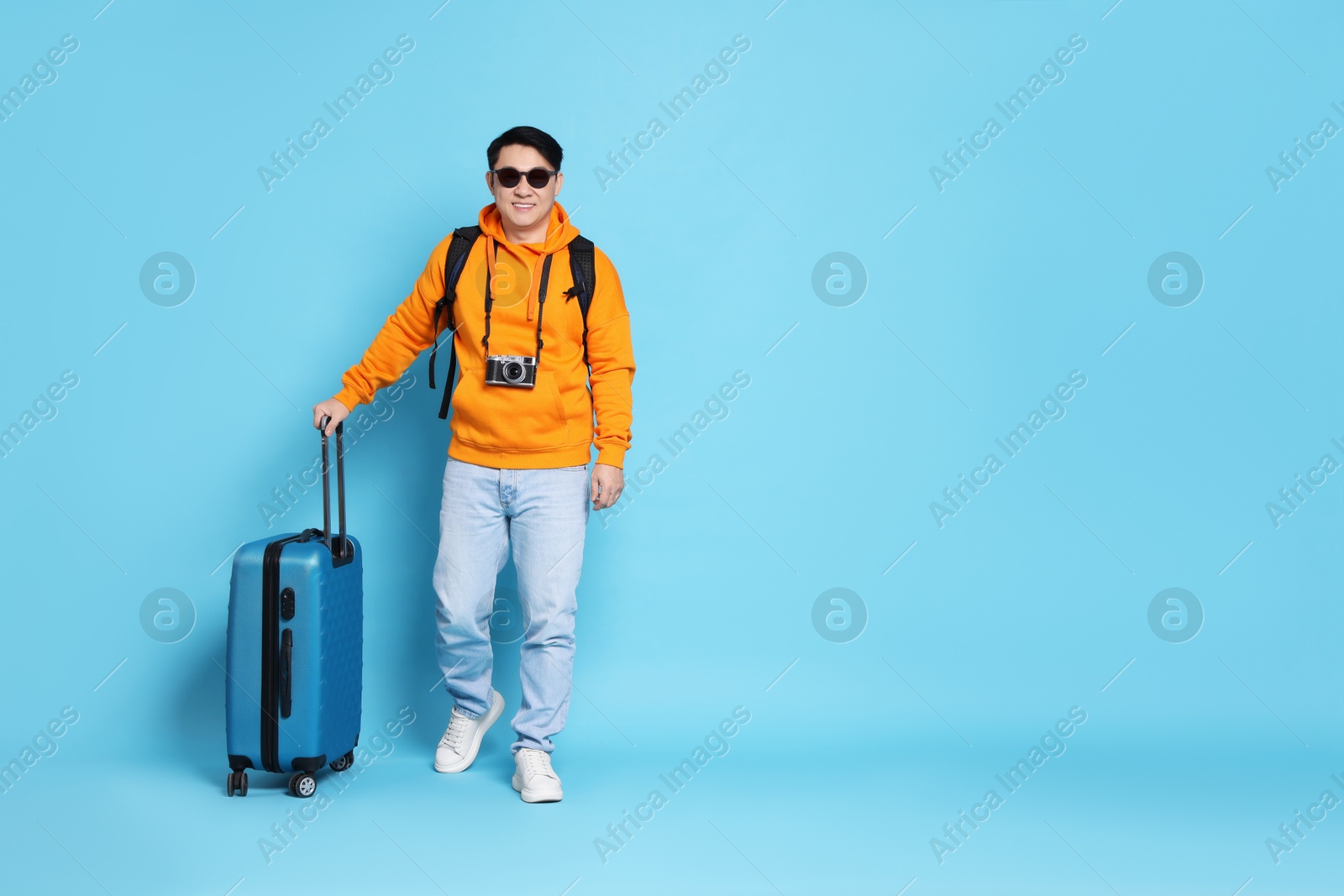 Photo of Traveller with suitcase on light blue background. Space for text