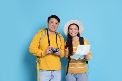 Photo of Happy travellers with camera and map on light blue background