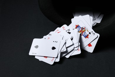 Photo of Playing cards and hat on black background, closeup