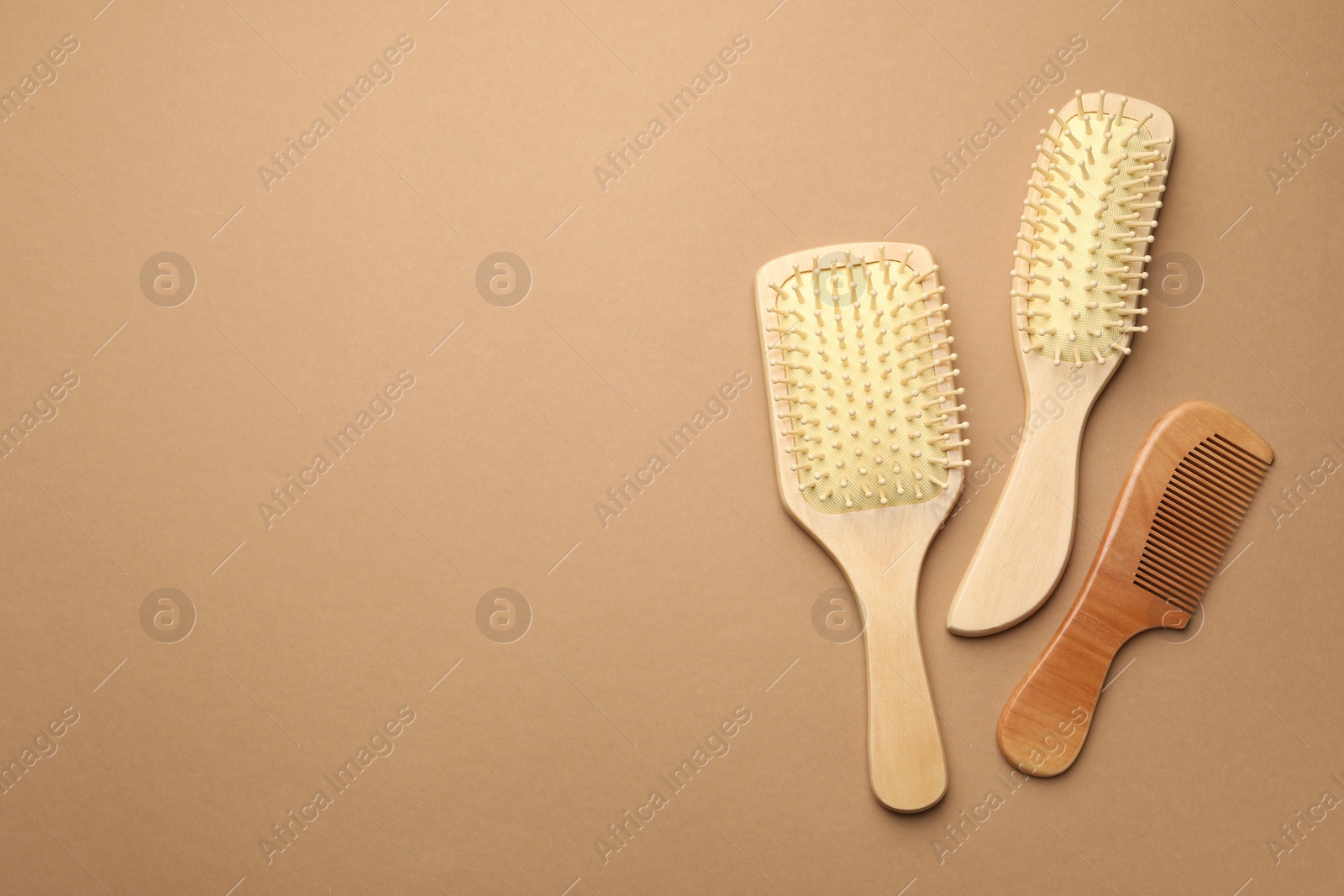 Photo of Wooden hair brushes and comb on beige background, top view. Space for text