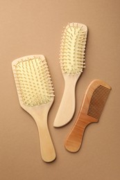 Photo of Wooden hair brushes and comb on beige background, top view