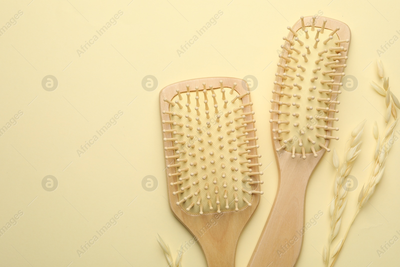 Photo of Wooden hair brushes and spikes on beige background, flat lay. Space for text