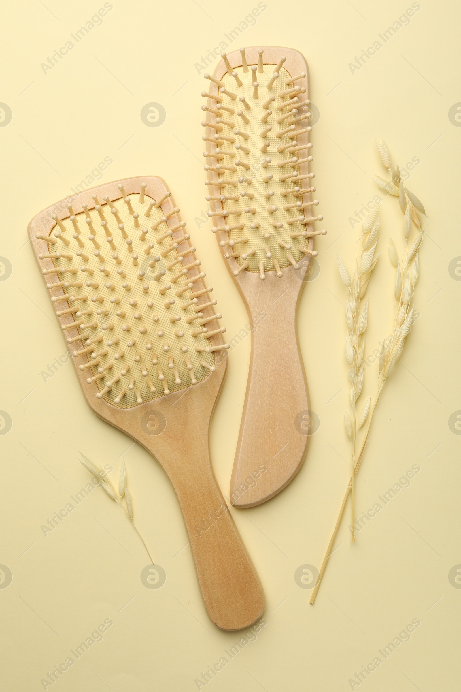 Photo of Wooden hair brushes and spikes on beige background, flat lay