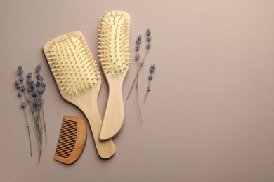 Photo of Wooden hair brushes, comb and lavender flowers on color background, flat lay. Space for text