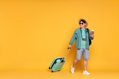 Photo of Traveller with passport and suitcase on yellow background. Space for text