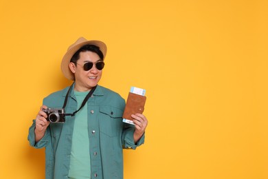 Photo of Happy traveller with passport and camera on yellow background. Space for text