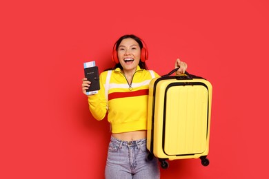 Photo of Happy traveller with passport and suitcase on red background