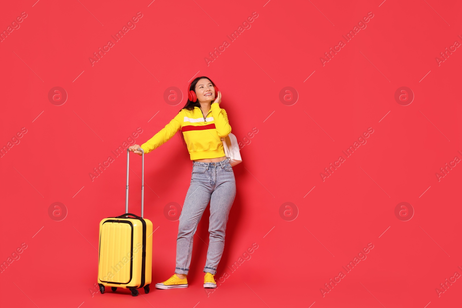 Photo of Happy traveller with suitcase on red background. Space for text