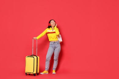 Photo of Happy traveller with suitcase on red background. Space for text