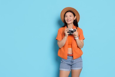 Photo of Happy traveller with camera on light blue background. Space for text