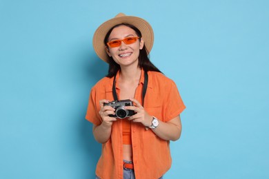 Photo of Happy traveller with camera on light blue background