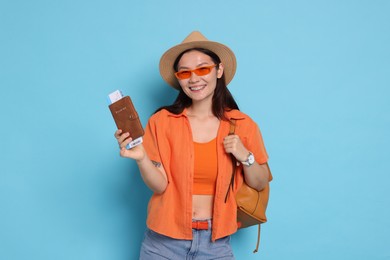 Photo of Happy traveller with backpack and passport on light blue background