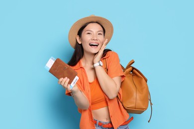 Photo of Happy traveller with backpack and passport on light blue background