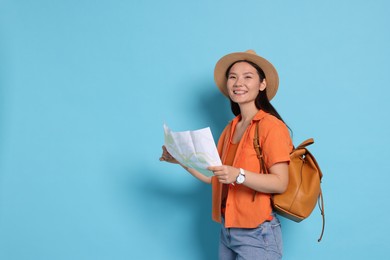 Photo of Happy traveller with backpack and map on light blue background. Space for text