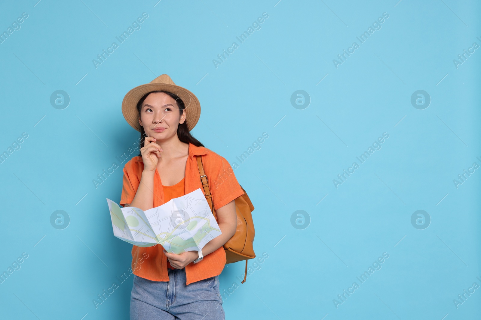 Photo of Pensive traveller with backpack and map on light blue background. Space for text