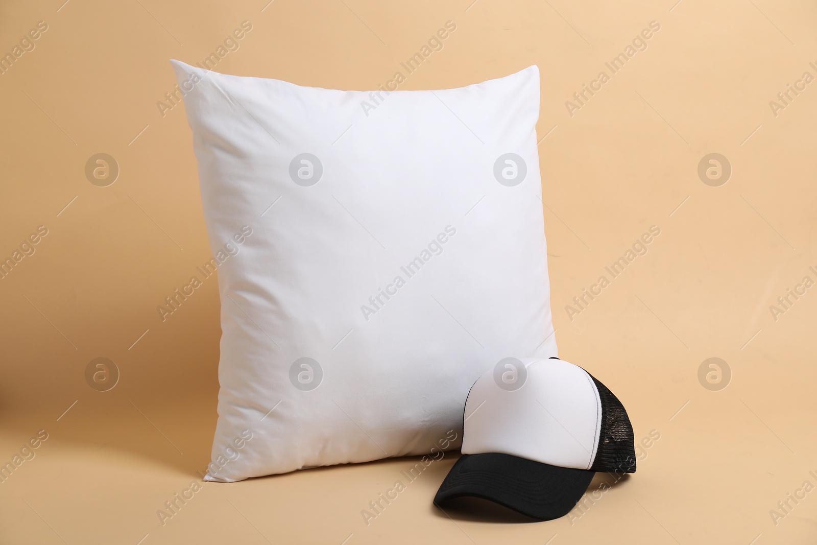 Photo of Blank pillow and baseball cap for branding on beige background. Mockup for design