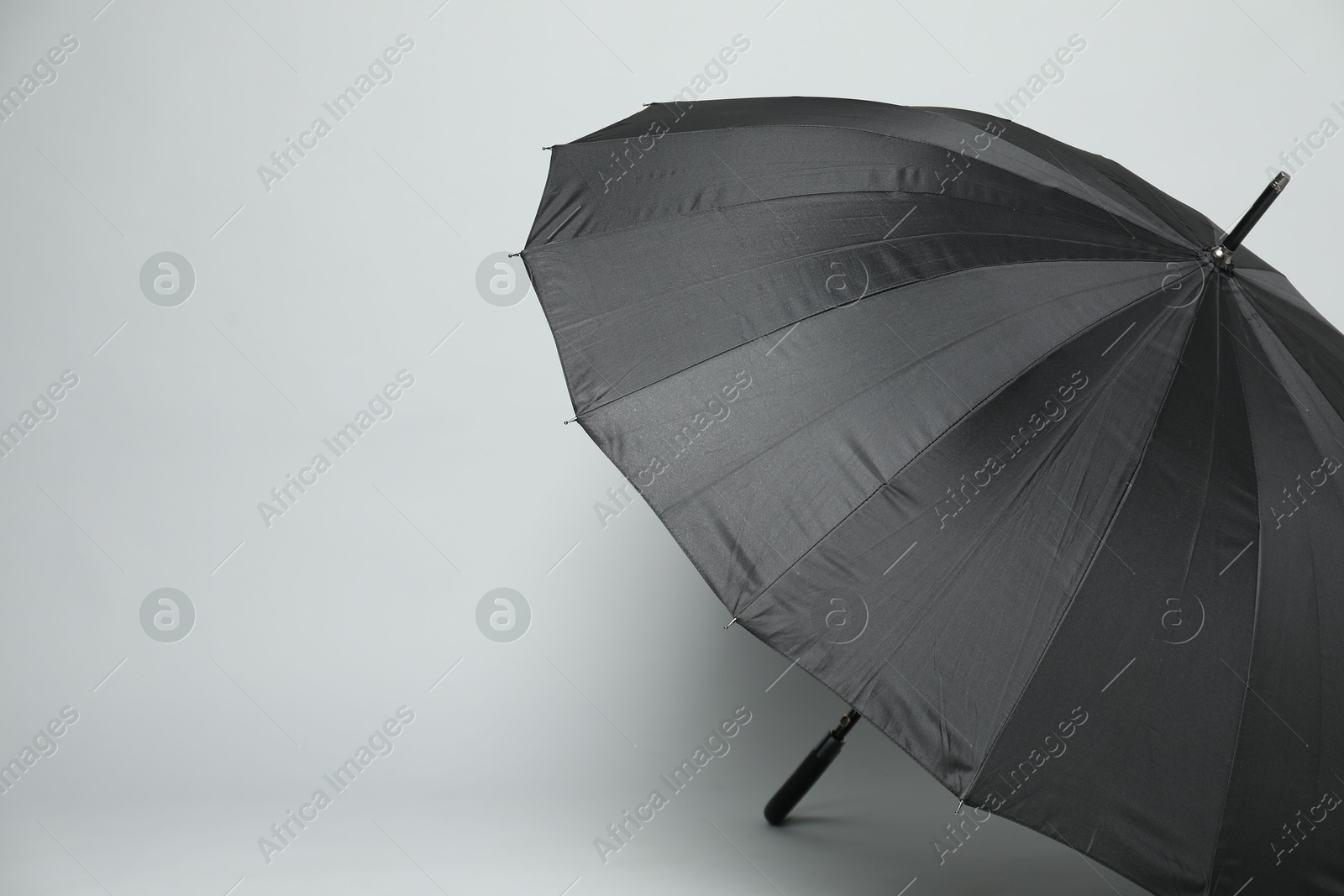 Photo of Open blank black parasol for branding on light grey background. Mockup for design