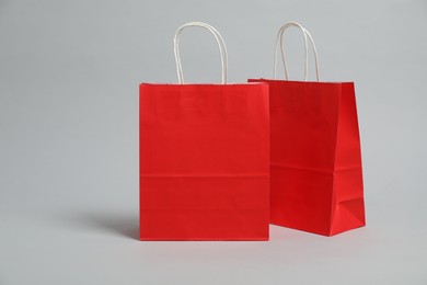 Photo of Two blank red shopping bags on light grey background. Mockup for design